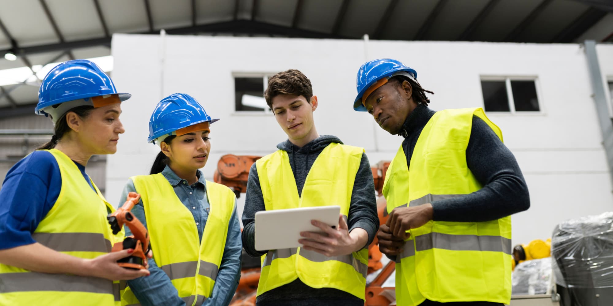 Group of multi-racial construction workers gather around tablet learning