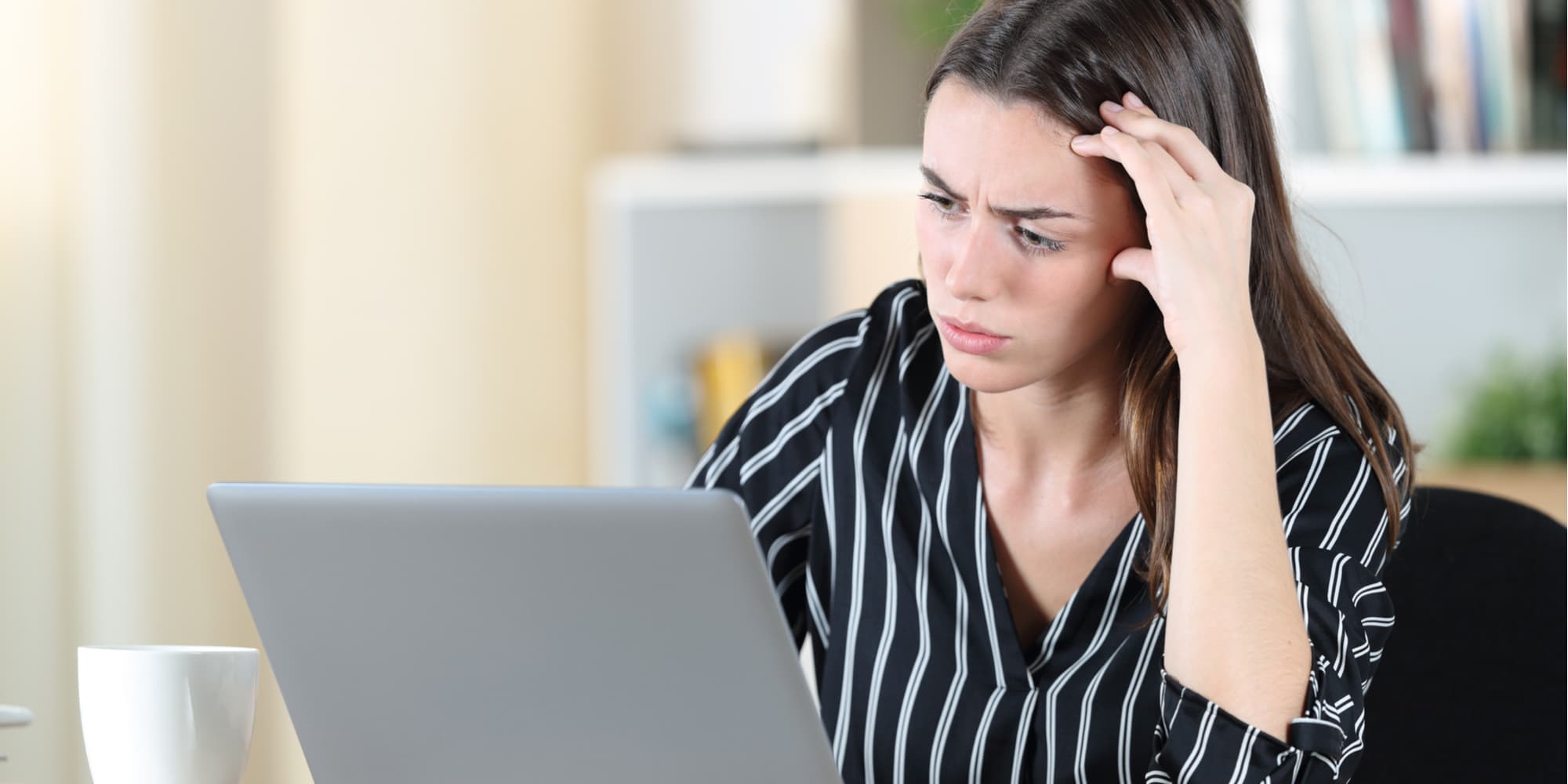 Young woman stares on computer screen with frustration and hand on forehead